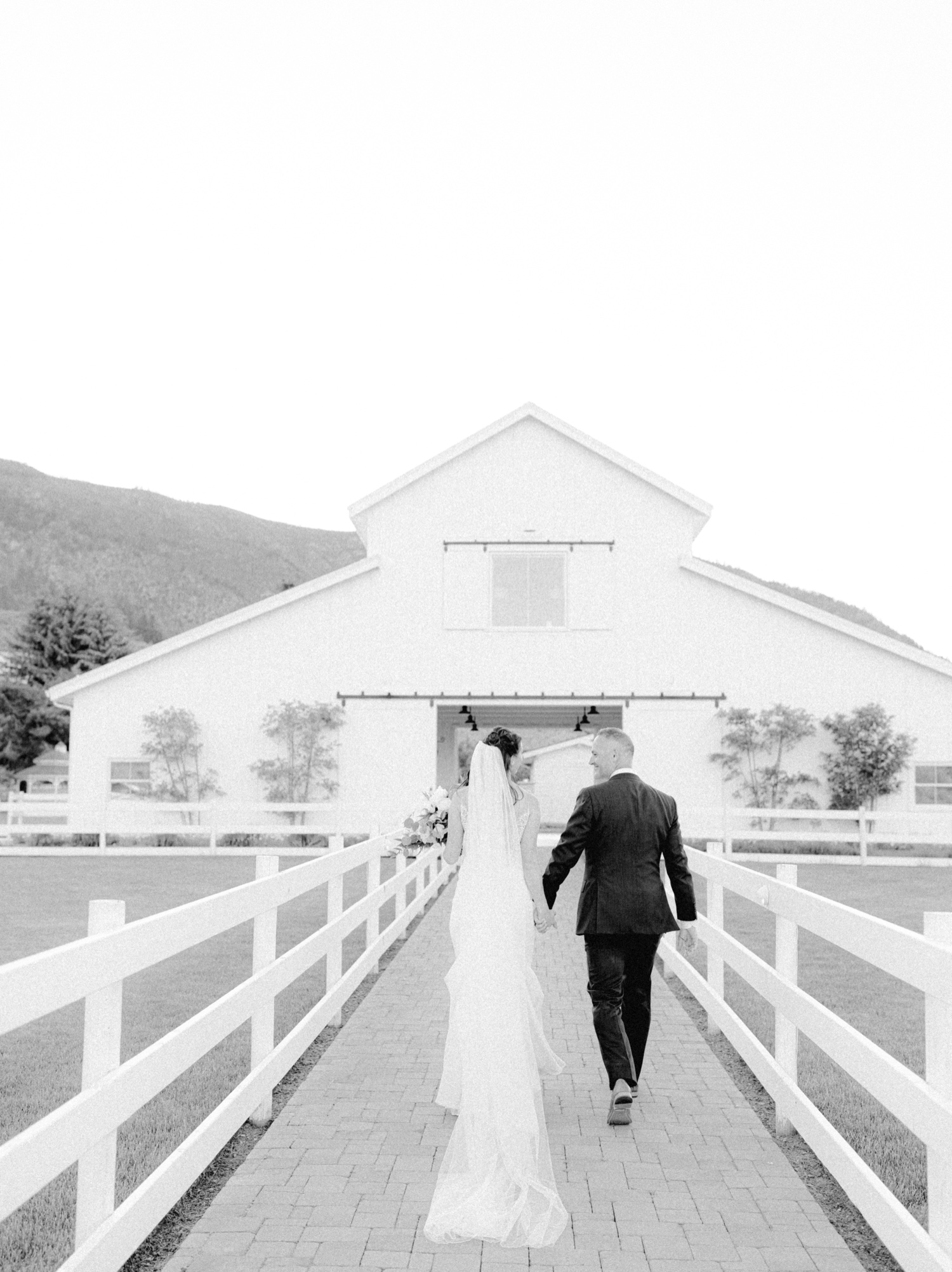 bride and groom walking towards ivory barn at harmony meadows