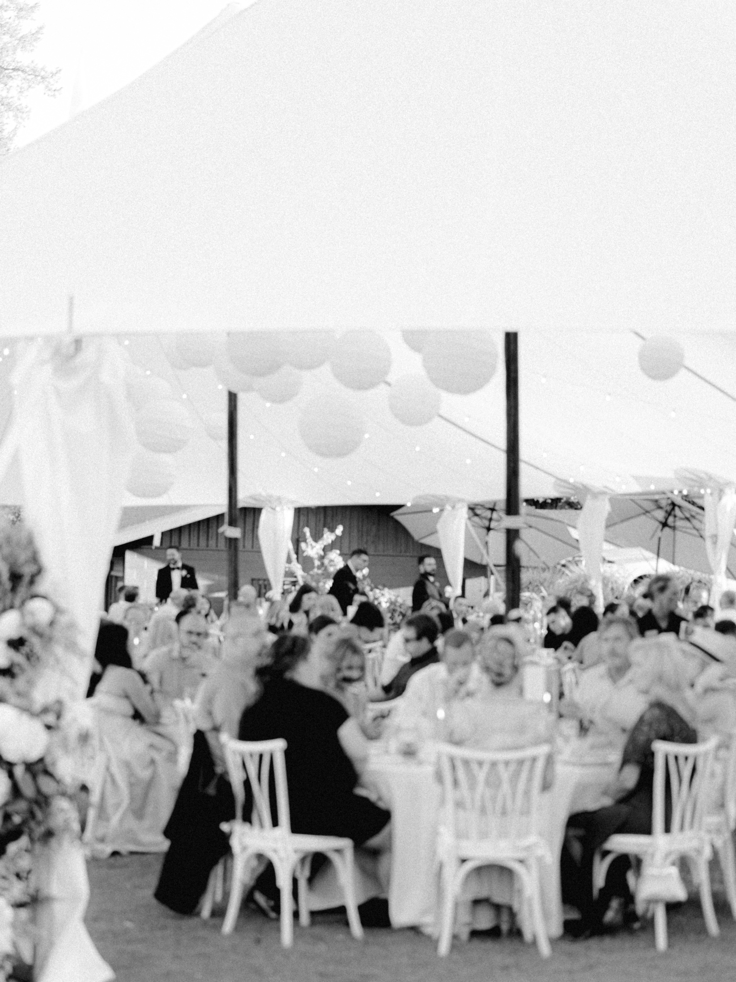 guests enjoying dinner under white sail tent for wedding reception at hayden lake country club