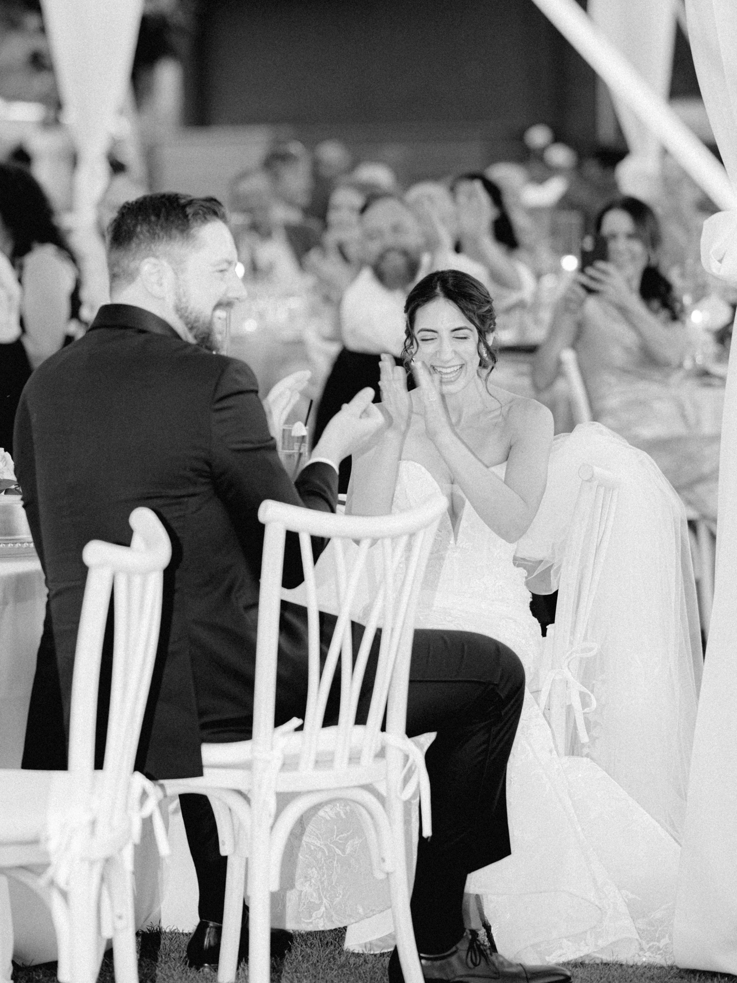 bride and groom laughing and clapping during wedding reception speech