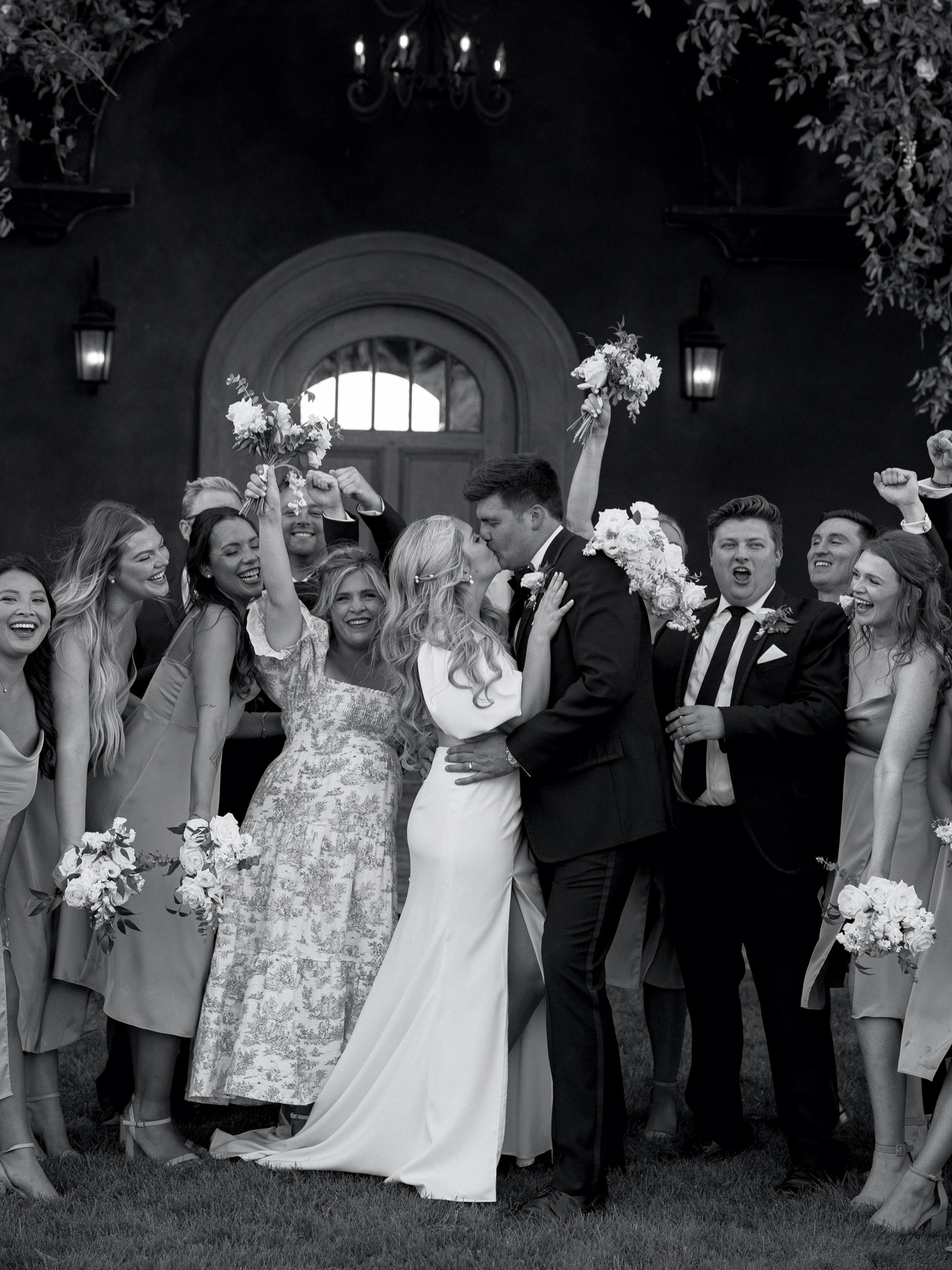 bride and groom share a kiss in front of bridal party