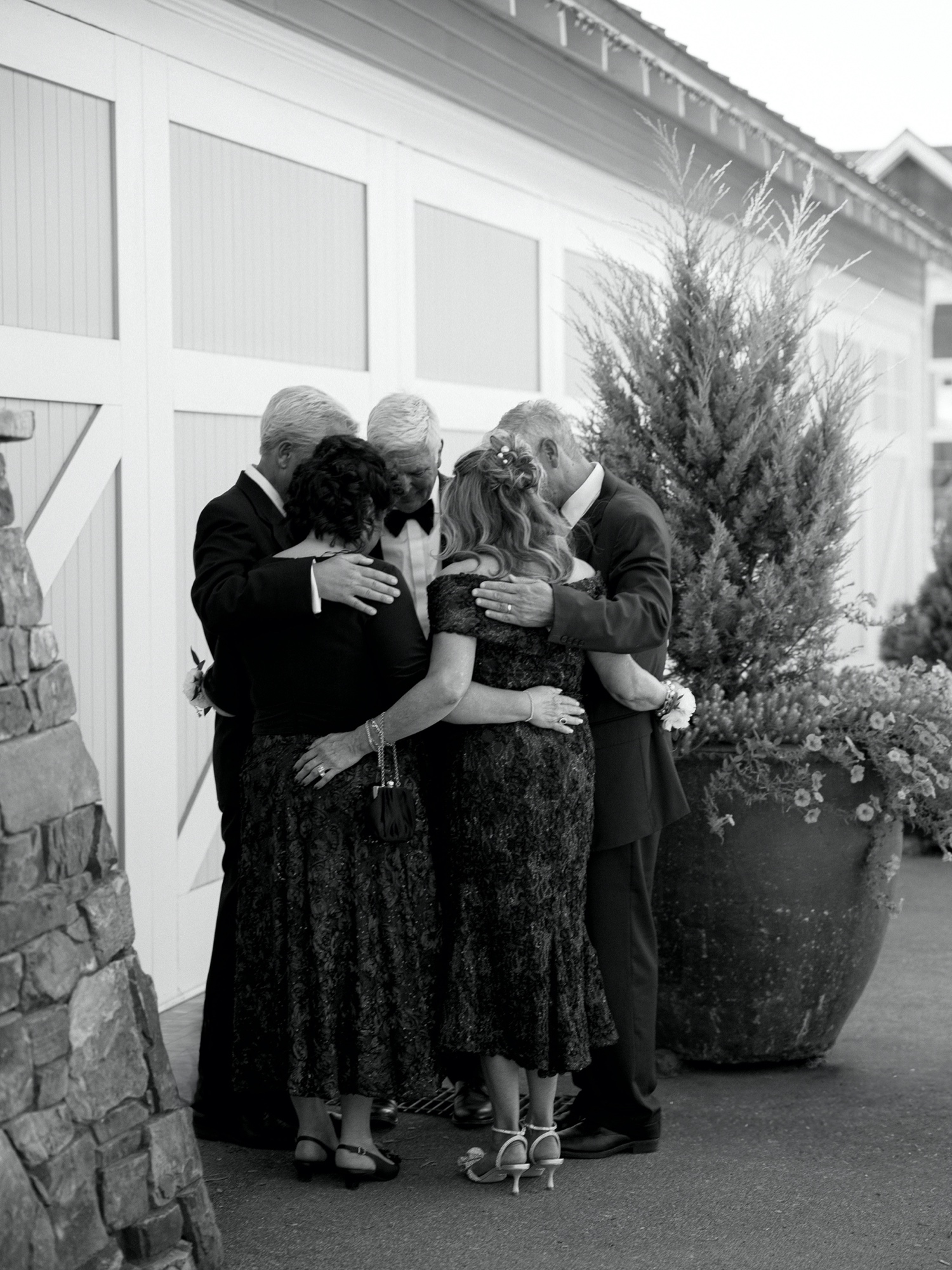 bride and grooms parents share a private prayer before wedding ceremony at abeja winery