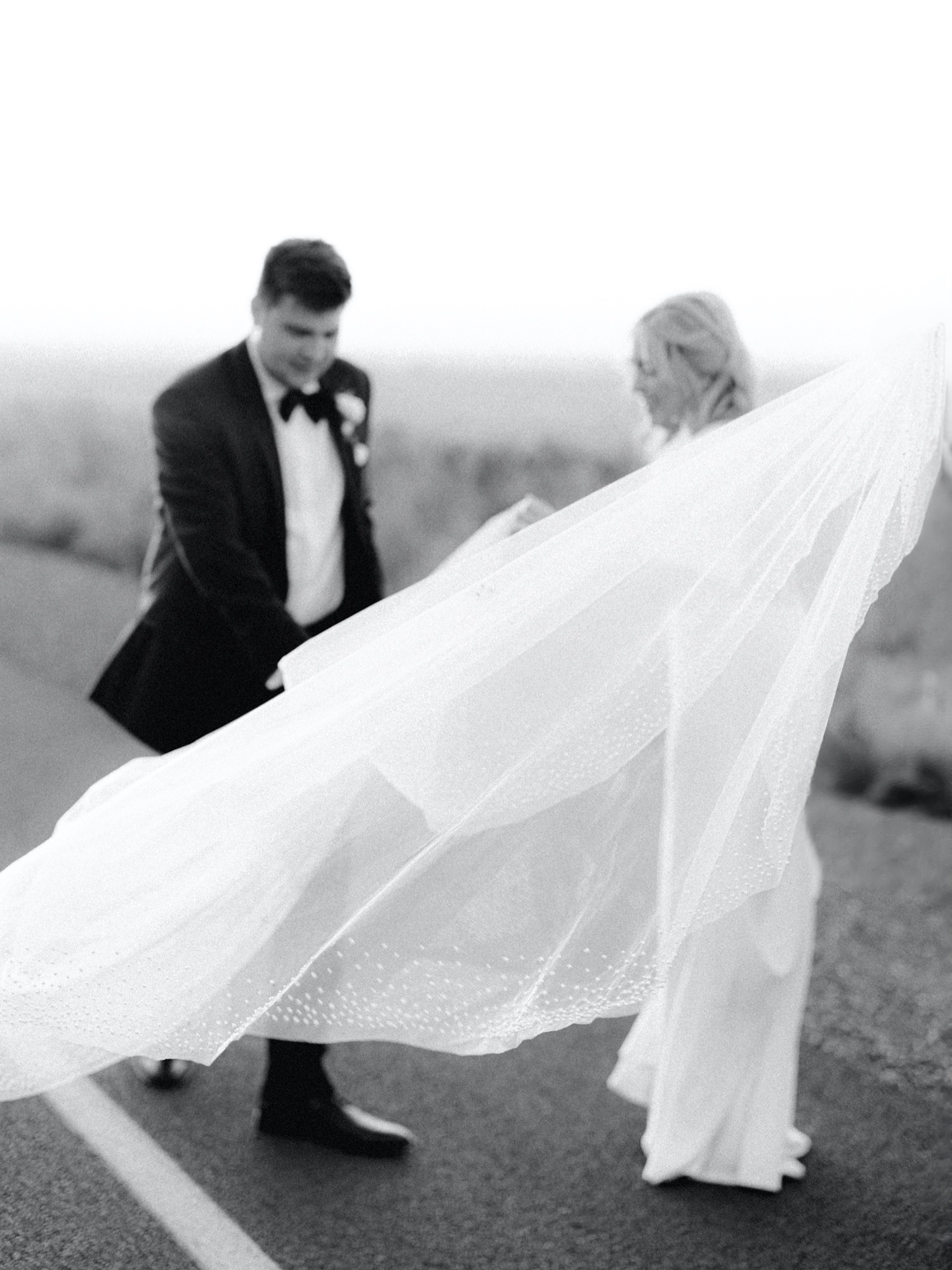 groom helps bride with veil during wedding day couple portraits