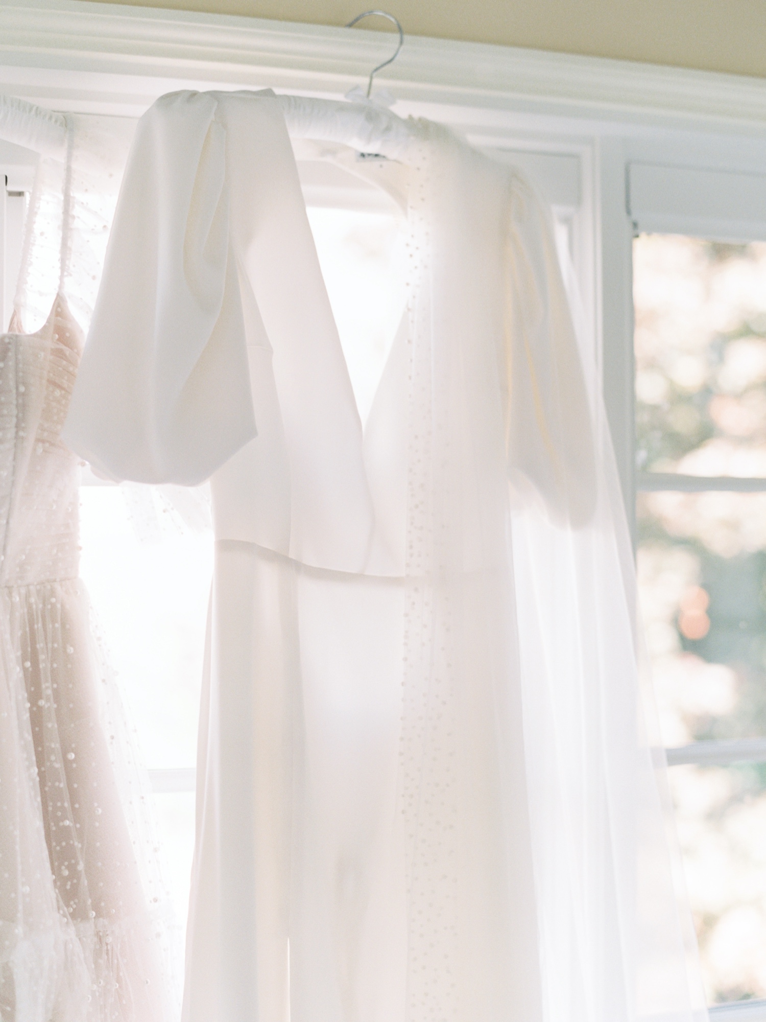 wedding dress and veil hanging in sunroom for abeja winery wedding