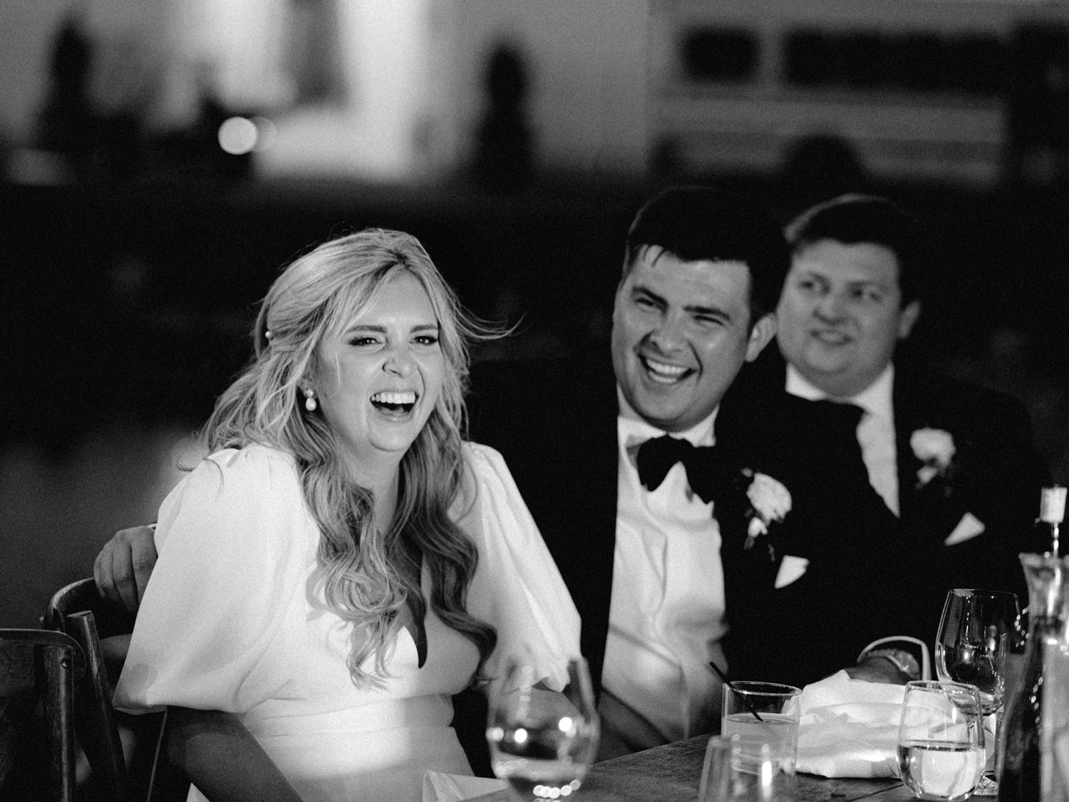 bride and groom laugh during toasts at wedding reception