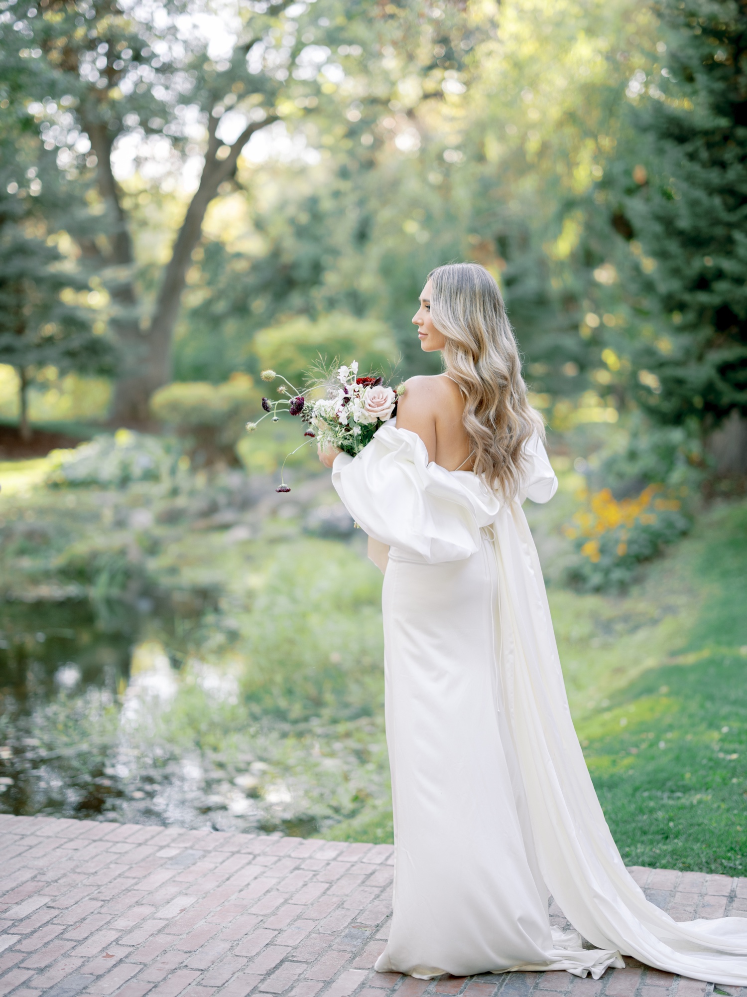 bride standing by pond at oakshire estate holding florals by haven flower farm